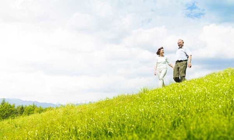 Happy couple taking a stroll through the green grass near Arcadia Senior Living Pace in Pace, Florida