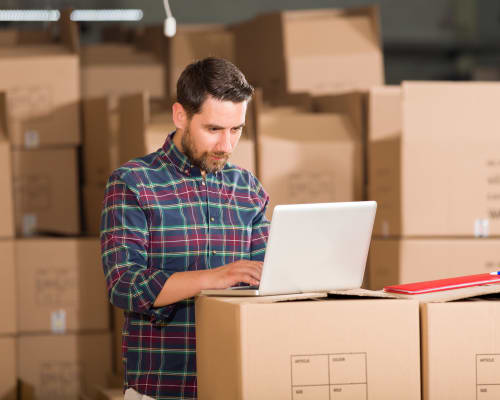 A man on his computer while moving boxes to A+ Storage in Davie, Florida