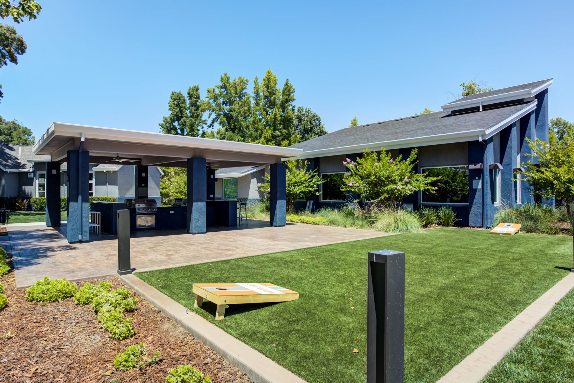 Corn hole and a covered outdoor BBQ area at The Woodlands Apartments in Sacramento, California