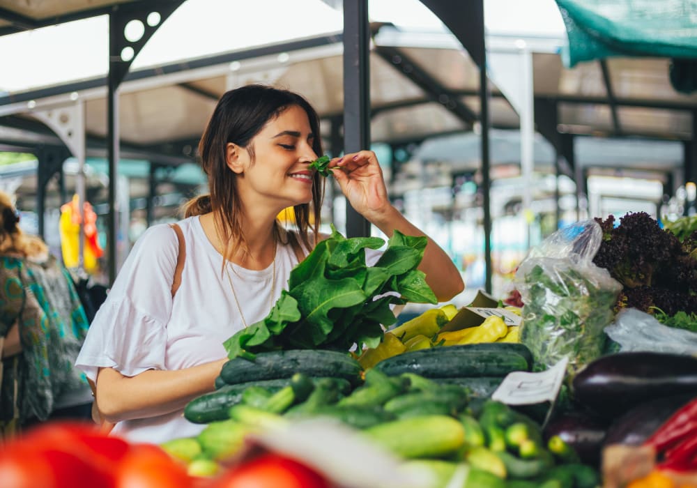 Resident smelling fresh herbs at an open-air farmers market near Sofi Warner Center in Woodland Hills, California