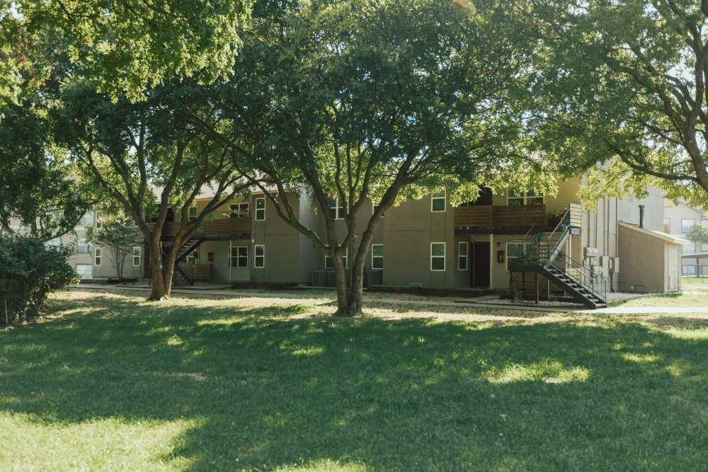 Exterior of apartments with well maintained lanscape at Lakeshore Villa Apartments in Rowlett, Texas