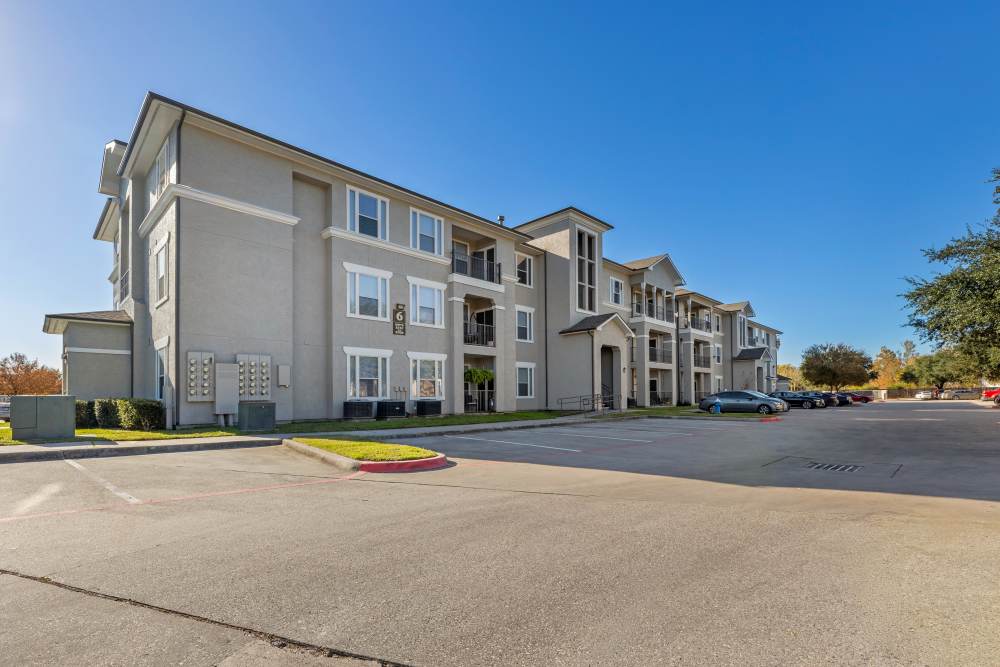  A wide exterior view of the apartment building with road and parking space at Costa Ibiza in Houston, Texas