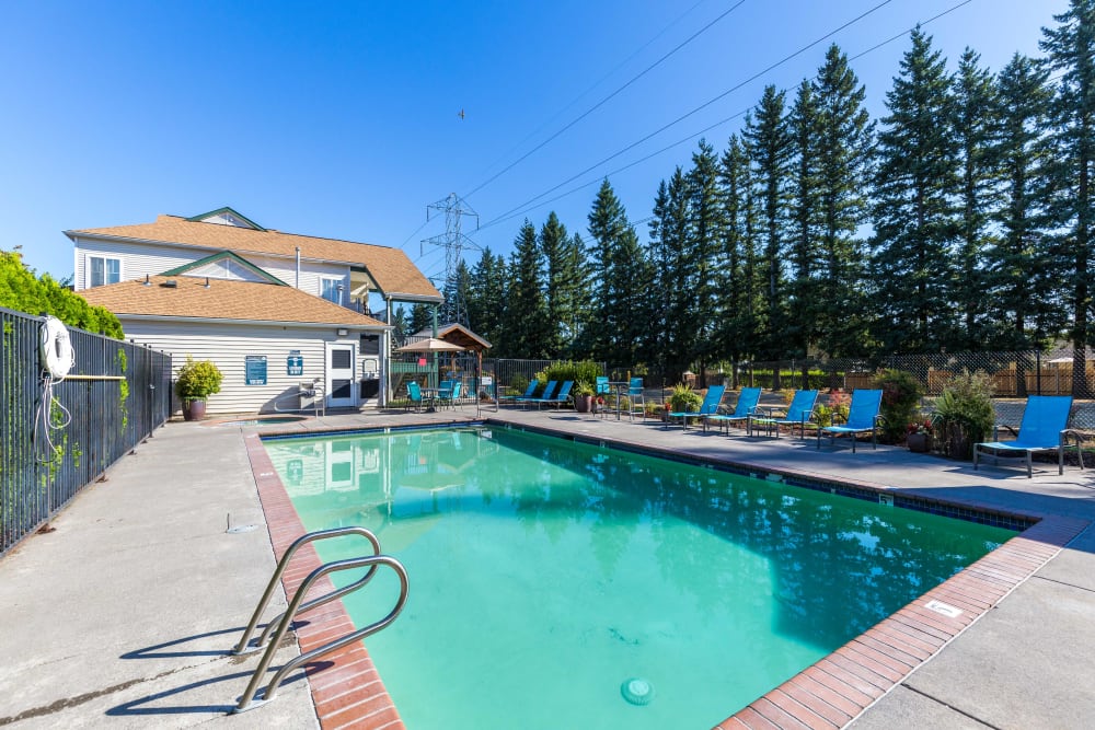 Beautiful resort-style swimming pool with lounge chairs at The Landings at Morrison Apartments in Gresham, Oregon
