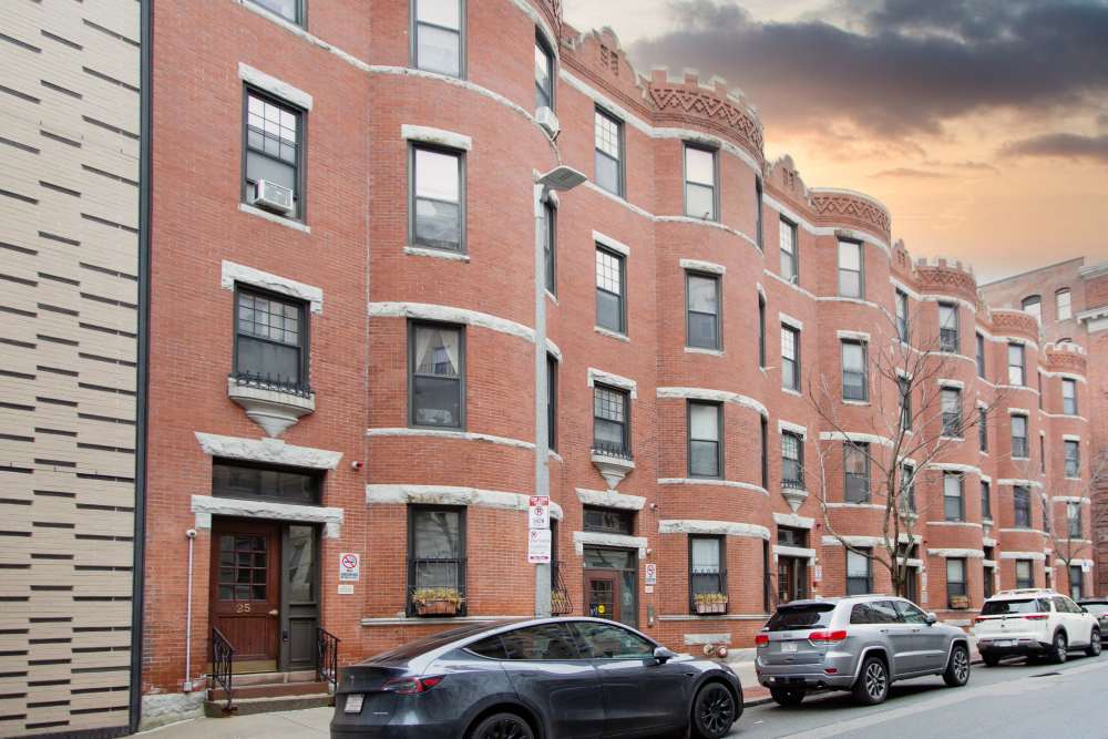 Brick apartment building with decorative cornices and large windows, street parking visible at 15-25 Hemenway Apartments in Boston, Massachusetts