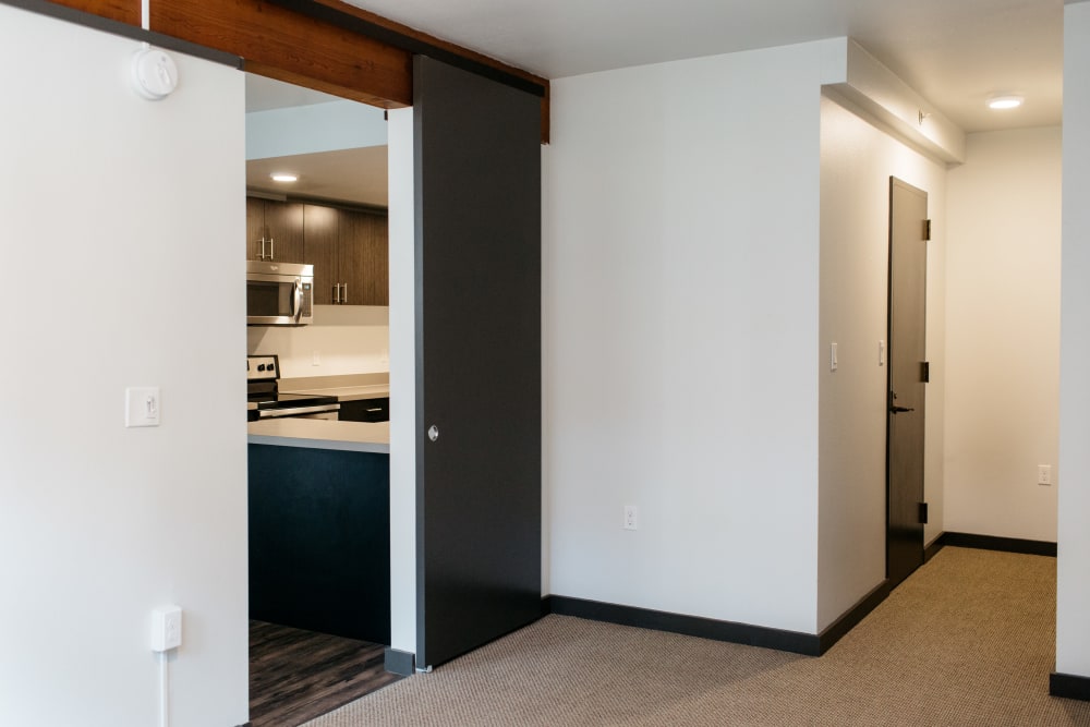 View of a carpeted room and entrance to the kitchen and dining area at MOD Apartments in Seattle, Washington