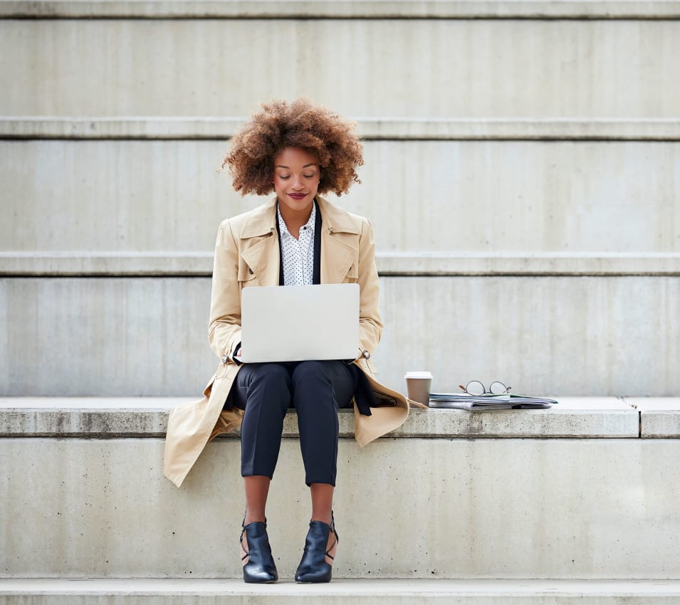 Resident working on her laptop on the steps outside her office near Villa Del Sol in Sunnyvale, California