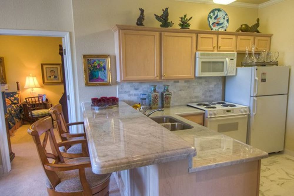 Kitchen with bar seating in senior living apartment at Mansion at Waterford Assisted Living in Oklahoma City, Oklahoma