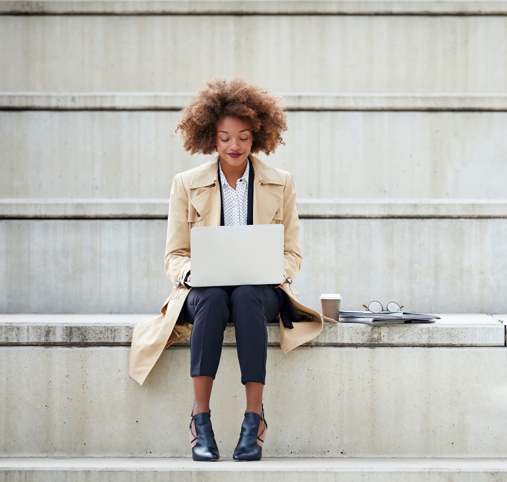 Resident working on her laptop on the steps outside her office near Skyline Terrace Apartments in Burlingame, California