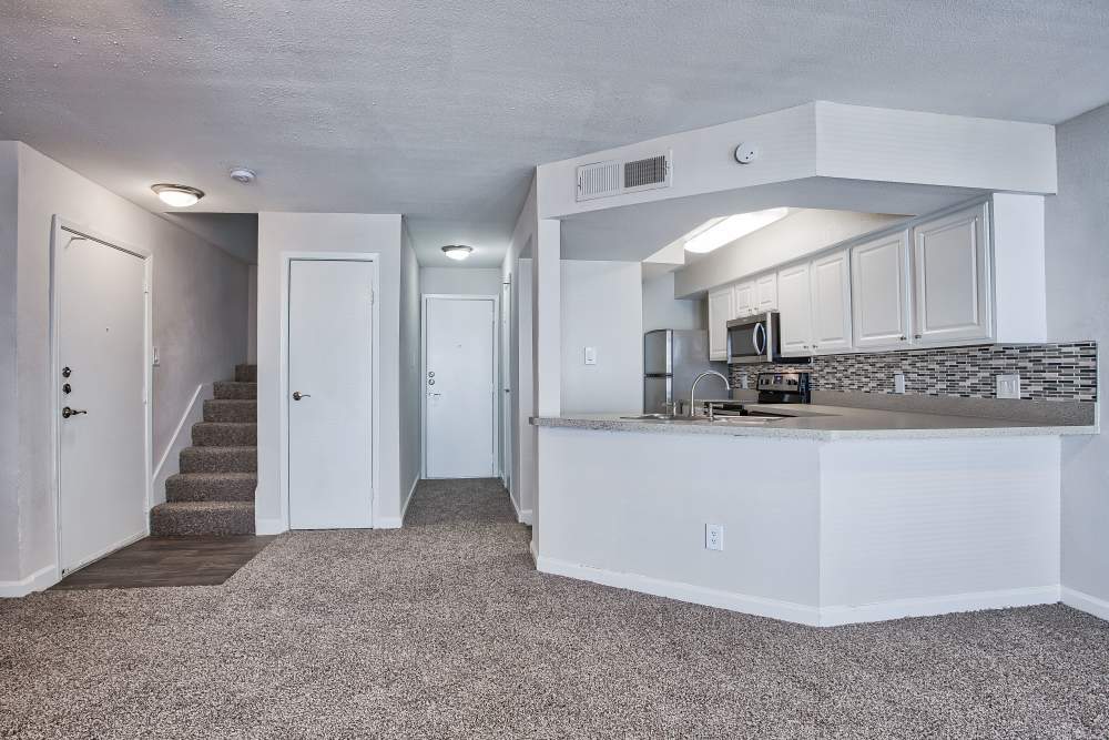 Modern apartment with view of kitchen and stairs to the next level at Branch Creek Apartments in Carrollton, Texas