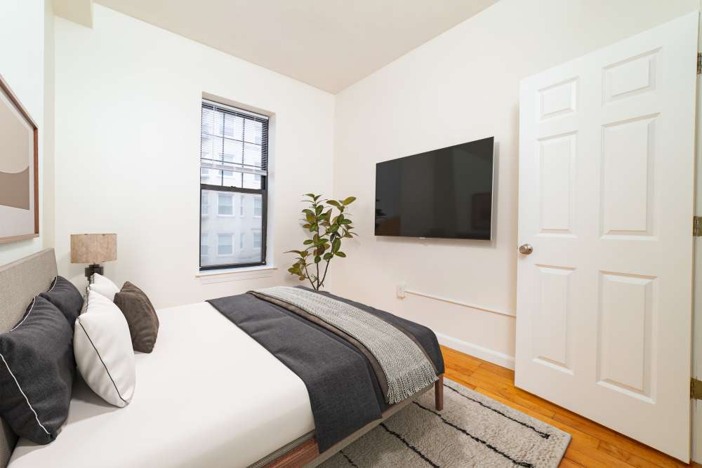 Garden style bed with gray blanket and decorative pillows at 15-25 Hemenway Apartments in Boston, Massachusetts
