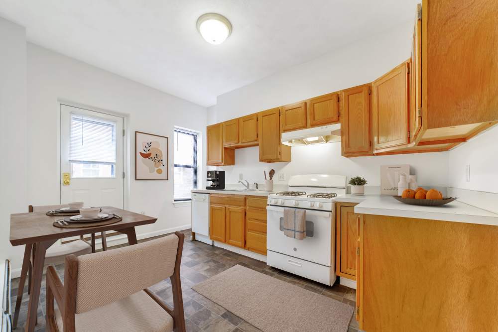 Garden style kitchen with wooden cabinets and dining table at 15-25 Hemenway Apartments in Boston, Massachusetts