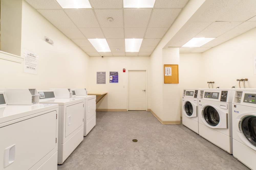 Bright laundry room featuring multiple washers and dryers with a folding area at 15-25 Hemenway Apartments in Boston, Massachusetts