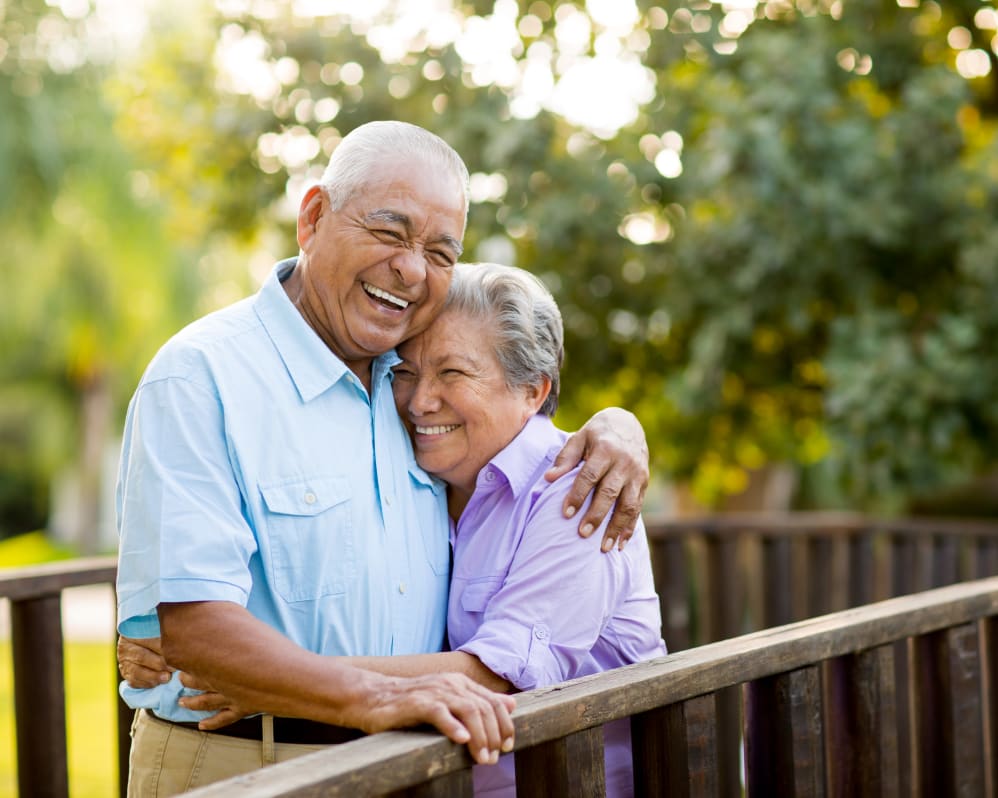 Resident couple hugging while standing on a bridge outside near Apple Creek Place in Appleton, Wisconsin.