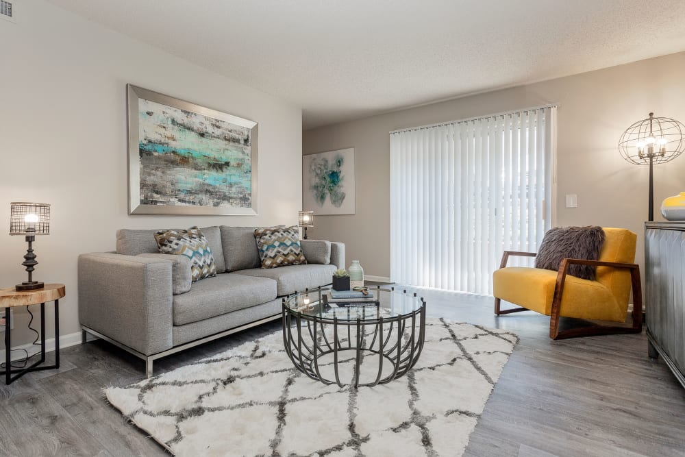 Model living room with luxury plank flooring and sliding door access to a private patio at Hickory Creek Apartments & Townhomes in Nashville, Tennessee