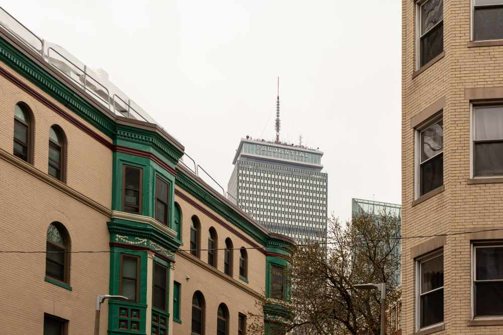 Historic buildings with green accents and modern skyscraper in the background at 15-25 Hemenway Apartments in Boston, Massachusetts