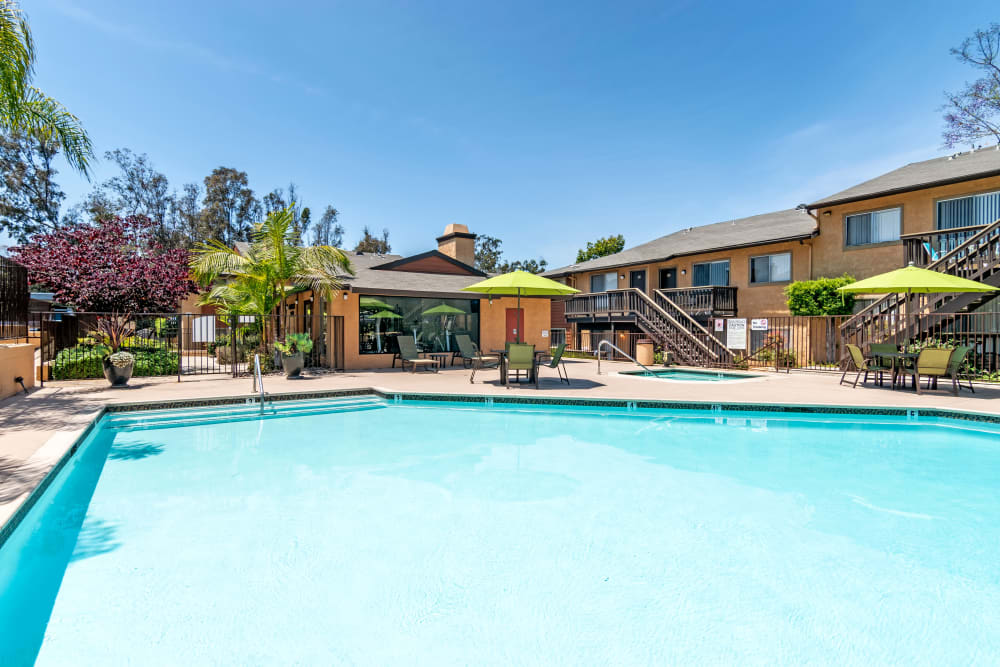 Beautiful resort-style swimming pool with lounge chairs and umbrellas at Hillside Terrace Apartments in Lemon Grove, California