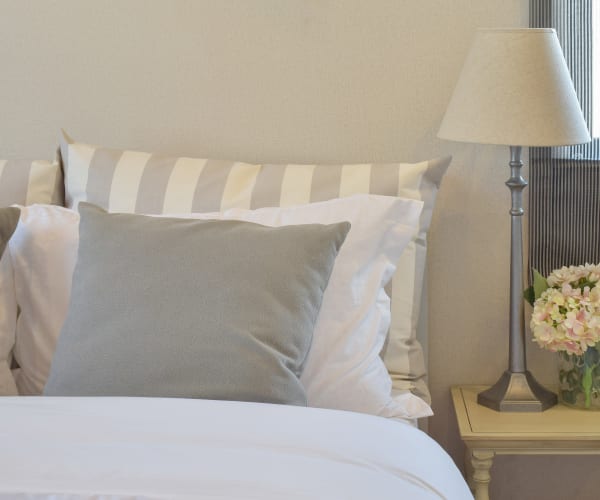 Modern bedroom interior with pillows on bed and decorative table lamp at Marian Towers home in Hoboken, New Jersey