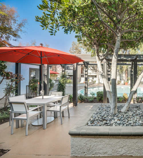 Outdoor seating with umbrellas beside the pool at The Villas at Rowland Heights in Rowland Heights, California