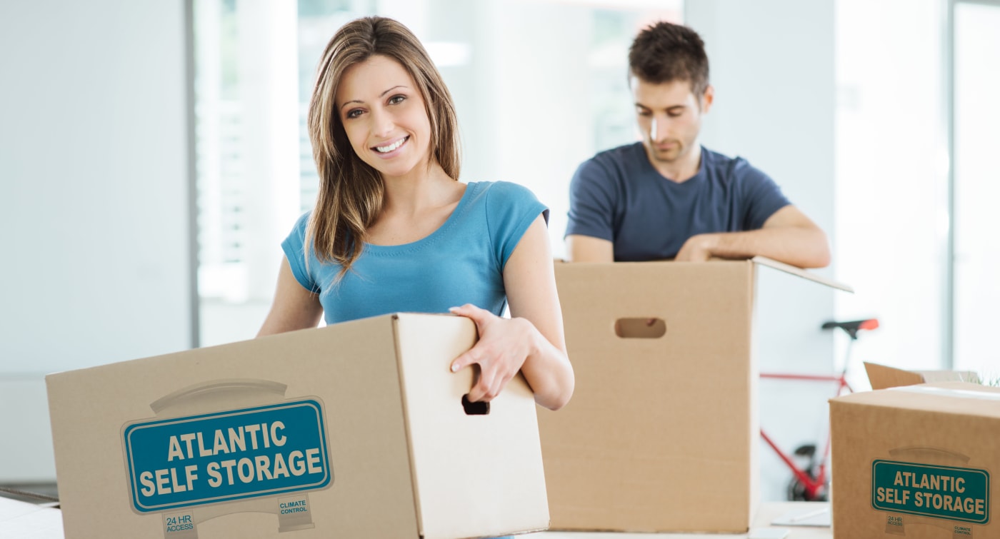 Couple moving into storage unit using boxes from Atlantic Self Storage in Jacksonville, Florida.