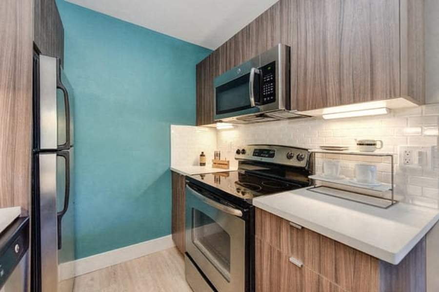 Apartments For Rent In Sunnyvale, CA - Citra - Kitchen With Wood-Style Cabinets, Energy-Efficient Appliances, Hardwood Floors, Refrigerator, Stove, And Microwave