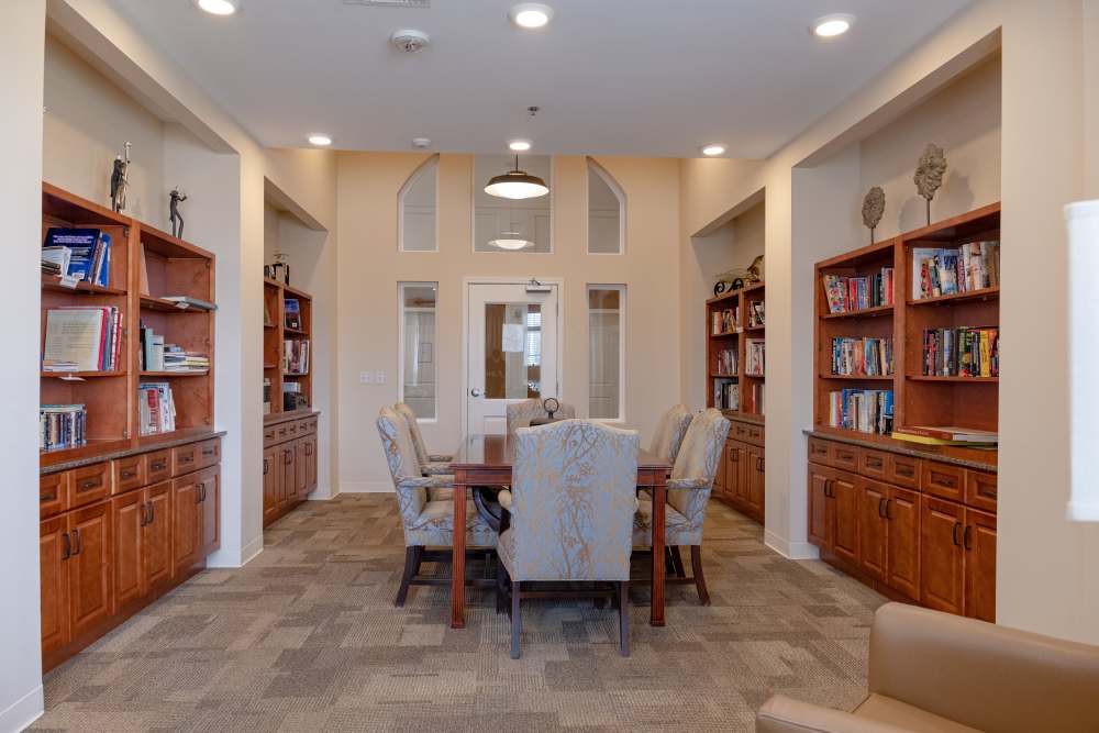 Reading room with multiple shelves of books and chairs at The Harmony Collection at Roanoke - Assisted Living in Roanoke, Virginia