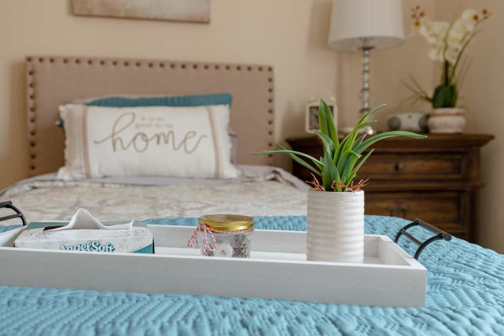 Cozy bedroom with side table at The Harmony Collection at Roanoke - Independent Living in Roanoke, Virginia