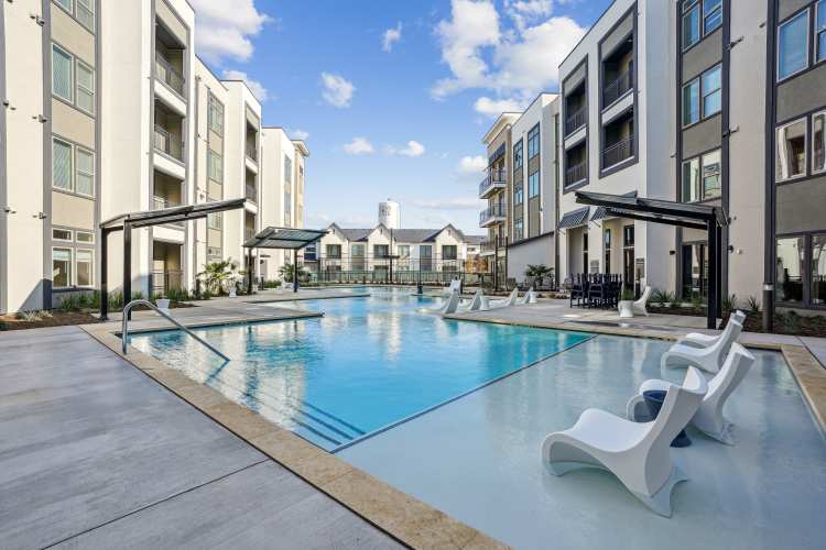 Community pool at active adult living apartments with modern apartment buildings in the background at Reserve at Round Rock in Round Rock, Texas