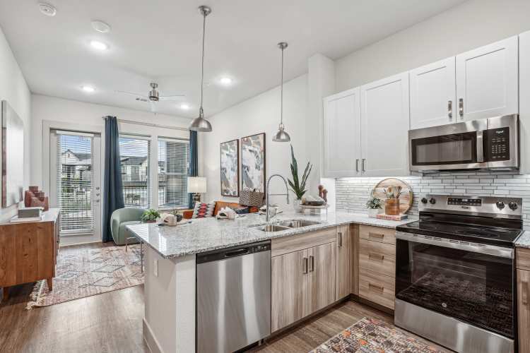 Modern kitchen in an active adult community apartment with a view through sliding glass doors onto a private balcony.