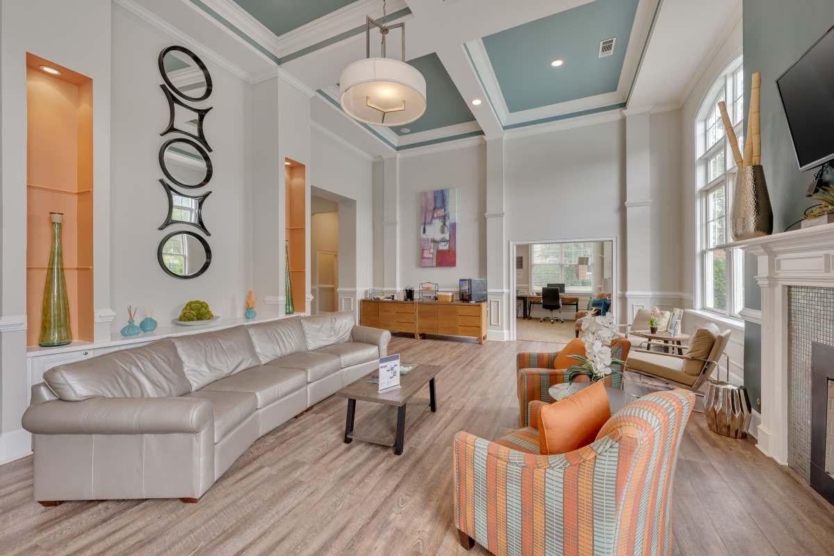 Community clubhouse with large couch, chairs and plank wood-style flooring at Kildaire Reserve Apartments in Cary, North Carolina