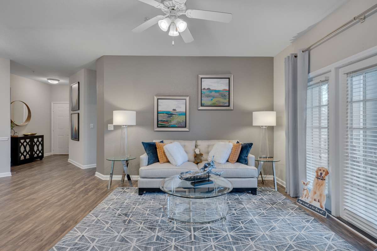 Spacious living room with large couch, ceiling fan and wood-style flooring at Kildaire Reserve Apartments, Cary, North Carolina