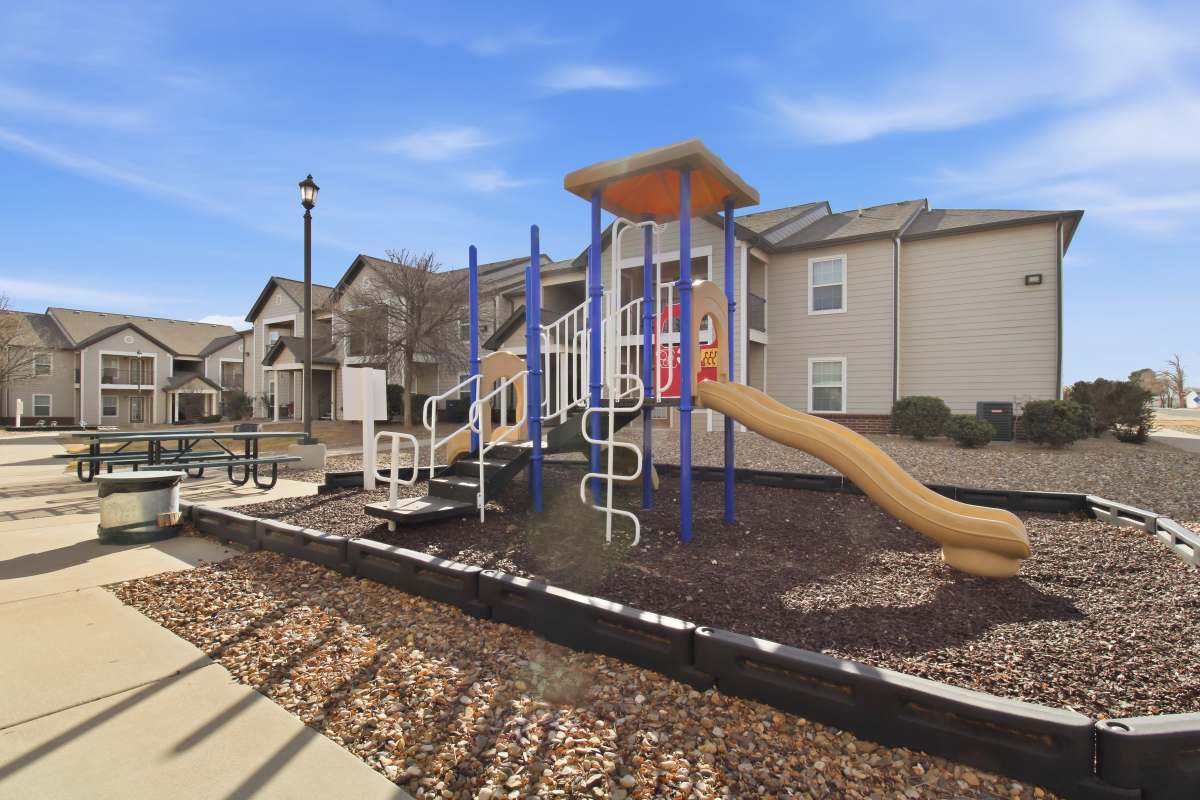 Playground with slide on mulch surface at Dunes Apartments in Seminole, Texas
