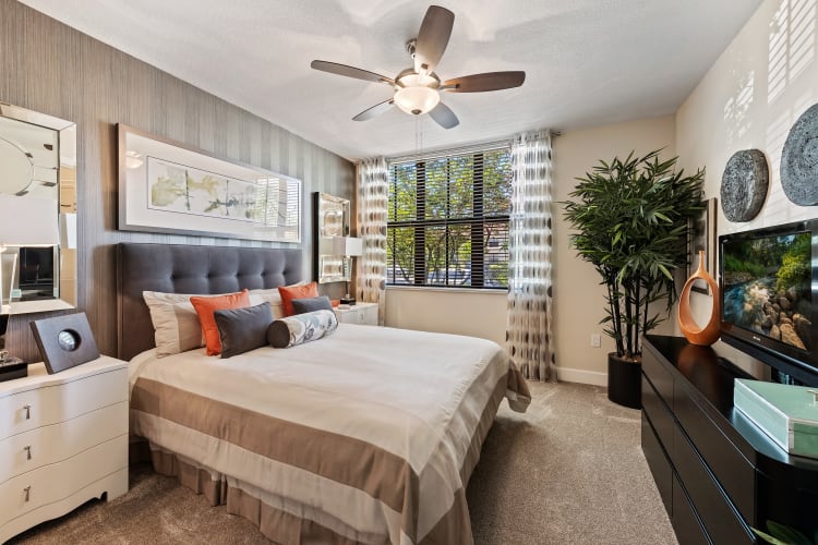 Well decorated model bedroom with plush carpeting and a ceiling fan at The Residences at Lakehouse in Miami Lakes, Florida