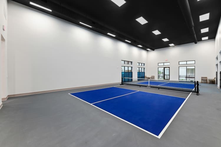 Indoor pickleball court with bright lighting and a polished playing surface at Watermere at Firewheel in Garland, Texas