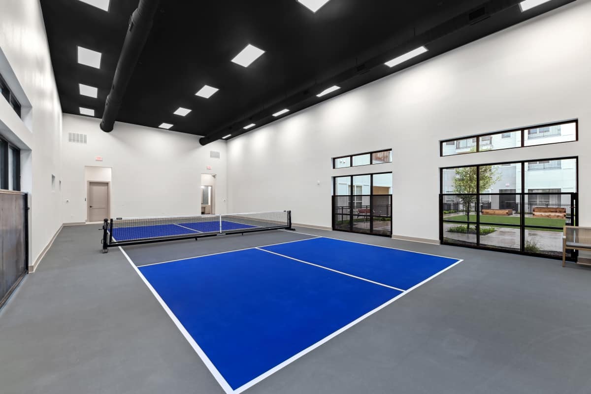 Brand-new indoor pickleball court with smooth flooring and bright overhead lighting at Watermere at Firewheel in Garland, Texas.