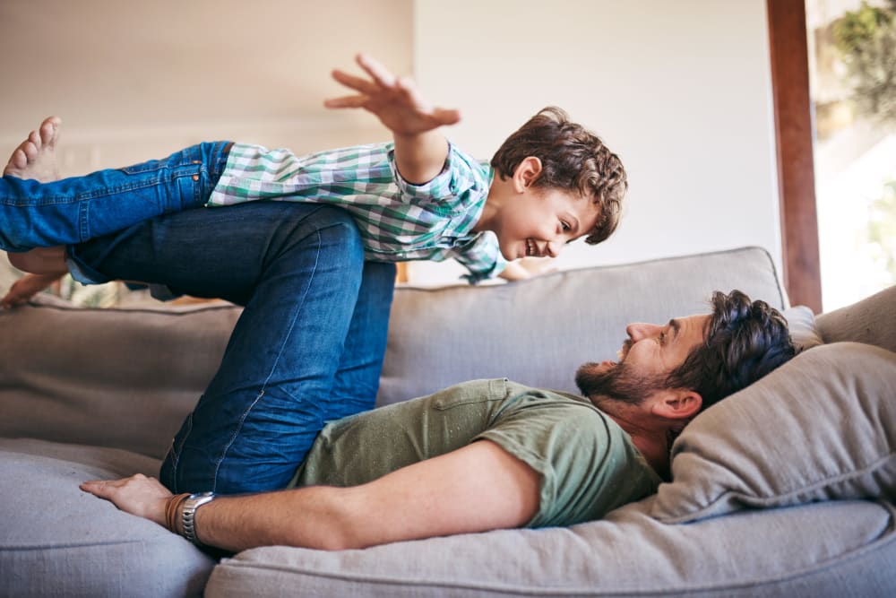 A father and son playing on a couch at One90 Main in Rowlett, Texas