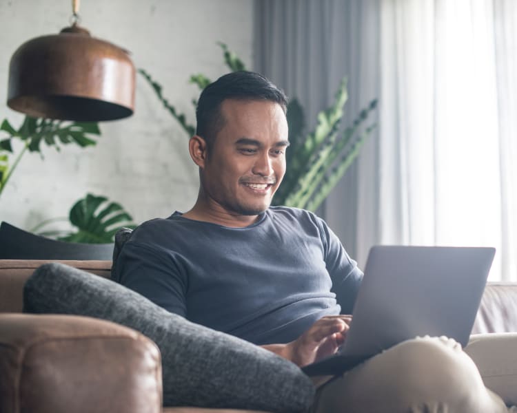 Resident filling out a form on our website on his laptop in his new home at Sofi Warner Center in Woodland Hills, California