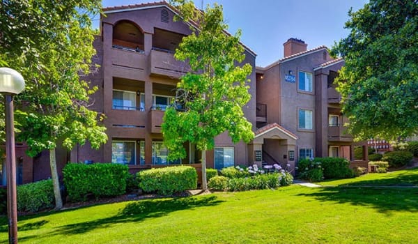Exterior Building View with Open Grass Area and Lush Trees and Landscaping at Sierra Del Oro Apartments in Corona