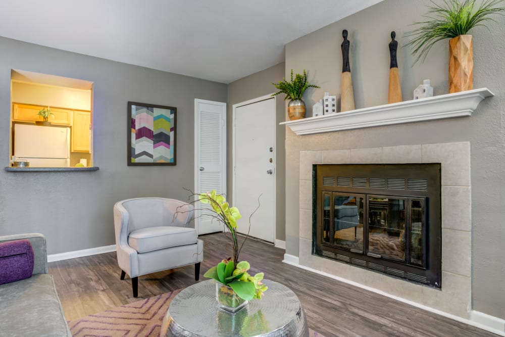 Model living room with hardwood style flooring and fireplace at EnVue Apartments in Bryan, Texas