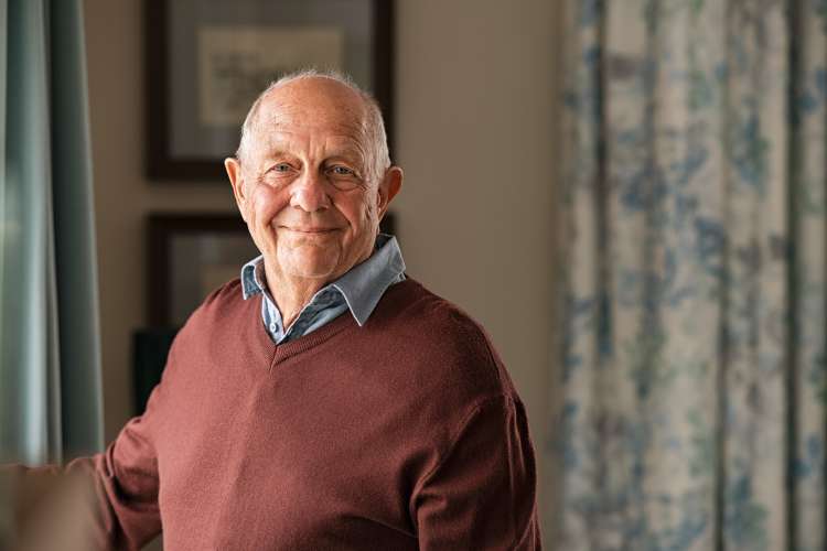 Senior man smiling while relaxing in his bright, comfortable apartment at Watermere Highlands in Arlington, Texas