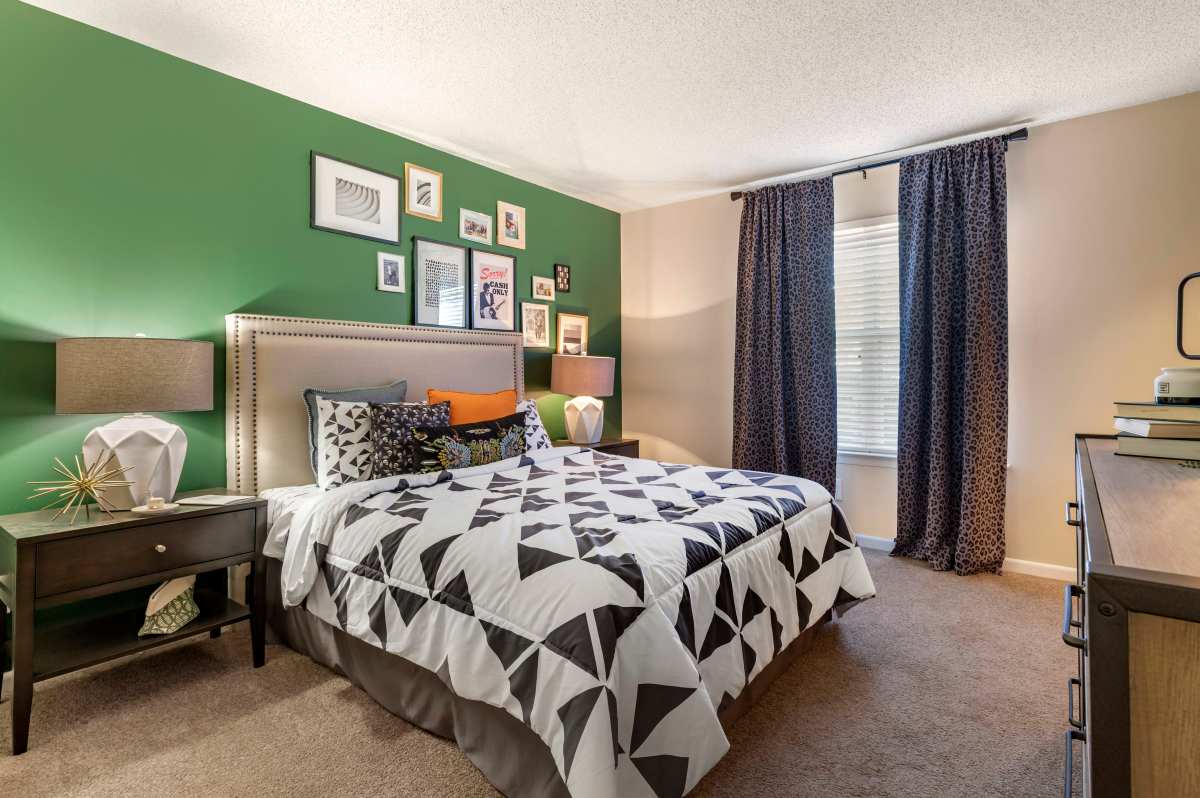 Comfortable bedroom with king size bed, large window and carpet flooring at Avenue at Harbison in Columbia, South Carolina