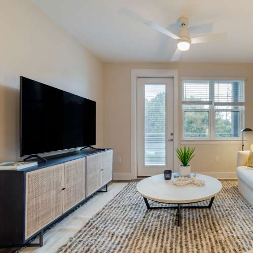 Apartment living room with tv and ceiling fan at The Calvert in Charlotte, North Carolina