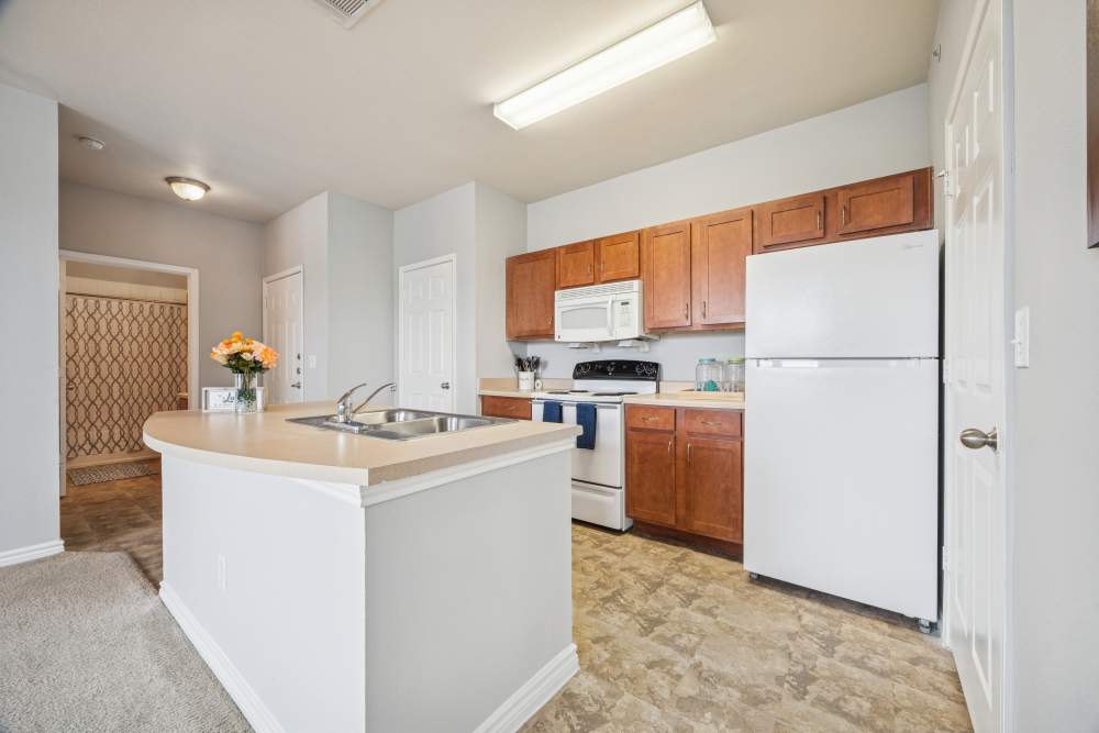 Bright kitchen with fully equipped with white appliances and island at The Cove at Palmer Point in Texas City, Texas