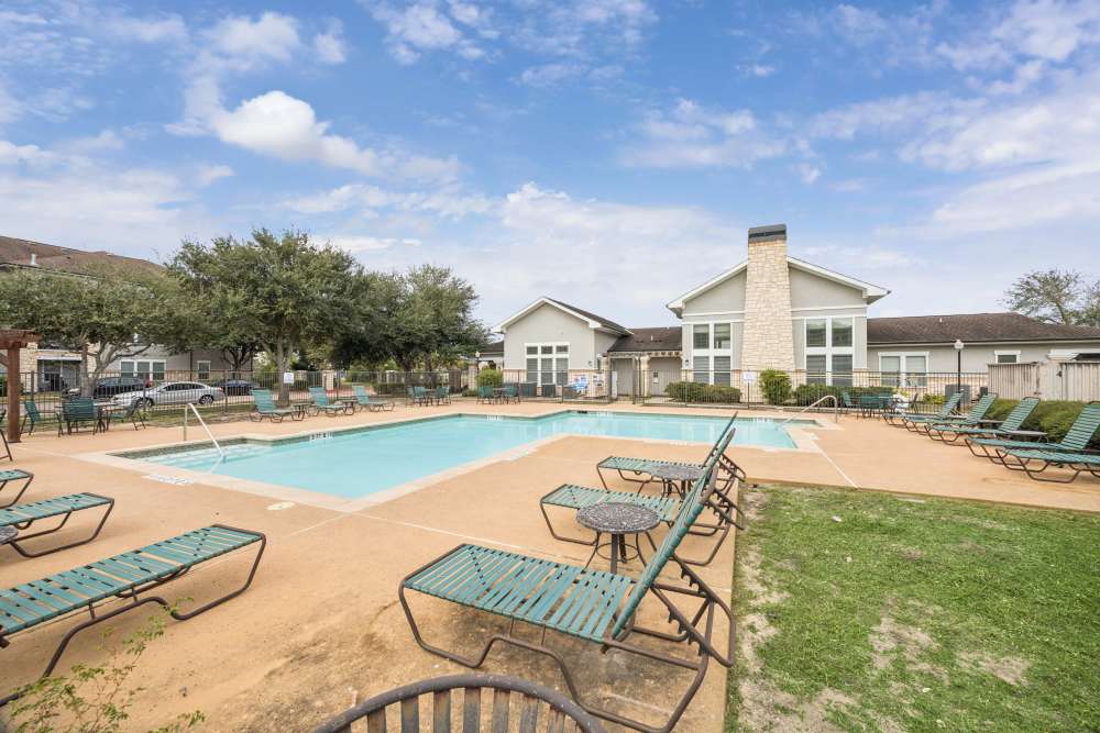Apartment swimming pool with lounge seating at The Cove at Palmer Point in Texas City, Texas