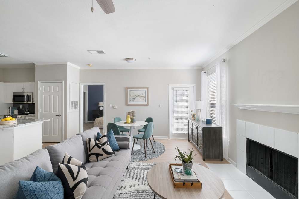 model unit living room with lots of natural light, modern furnishings, ceiling fan, fireplace, and wood-style flooring at Andover at Crabtree in Raleigh, North Carolina