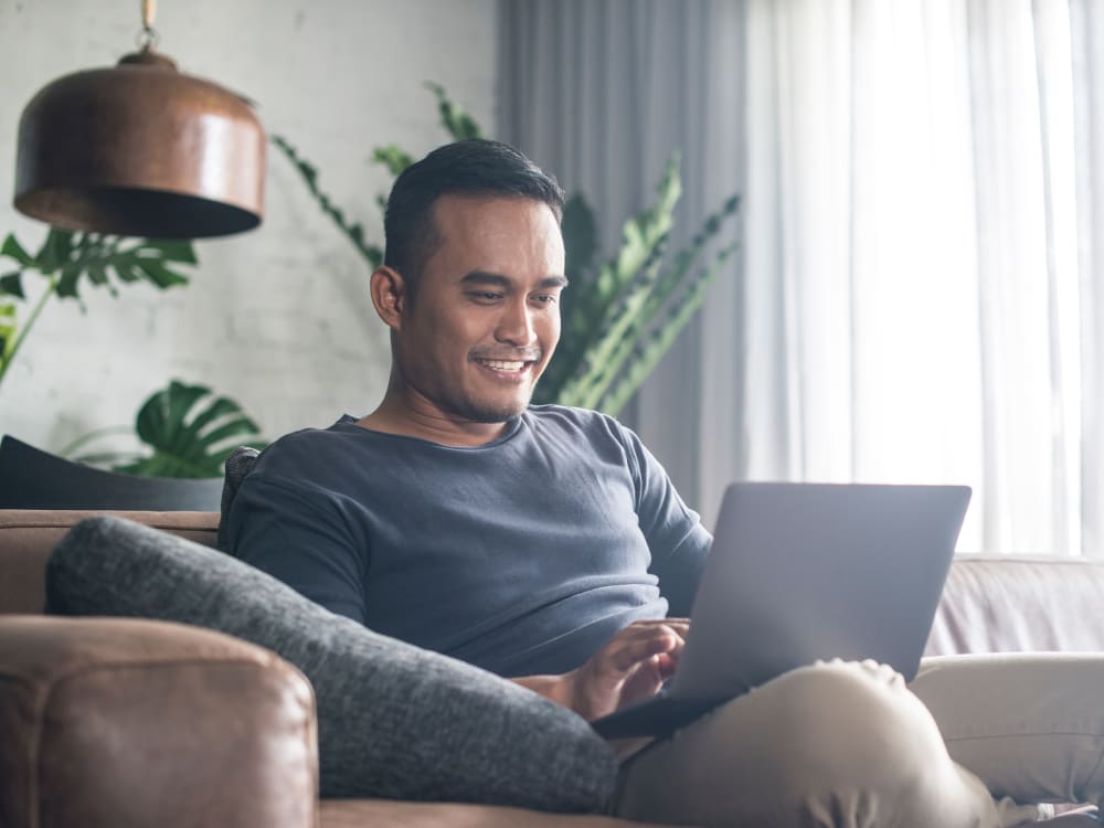 Resident filling out a form on our website on his laptop in his new home at Skyline Terrace Apartments in Burlingame, California