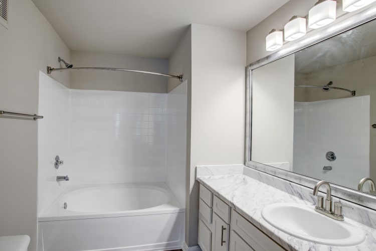 Large, well-lit bathroom with oversized vanity mirror in renovated home at Kenwood Club at the Park in Katy, Texas