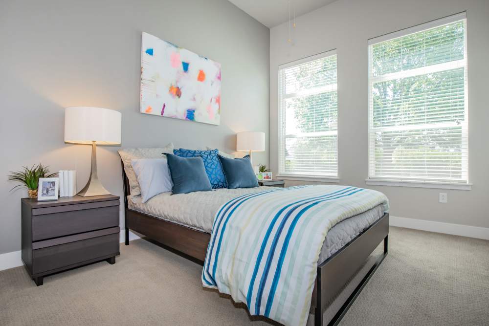 Comfortable bedroom with bed, large window and carpet flooring at Park Place Olde Town Apartments in Arvada, Colorado