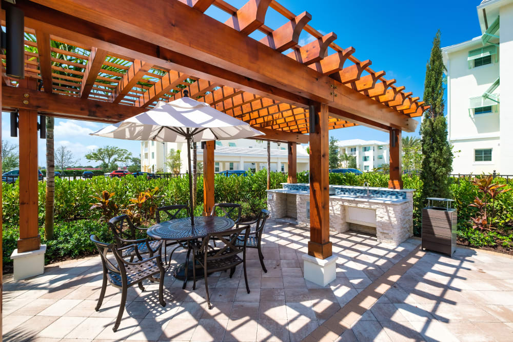 Outdoor grilling pavilion with a shaded table at Oceanside Lantana in Lantana, Florida