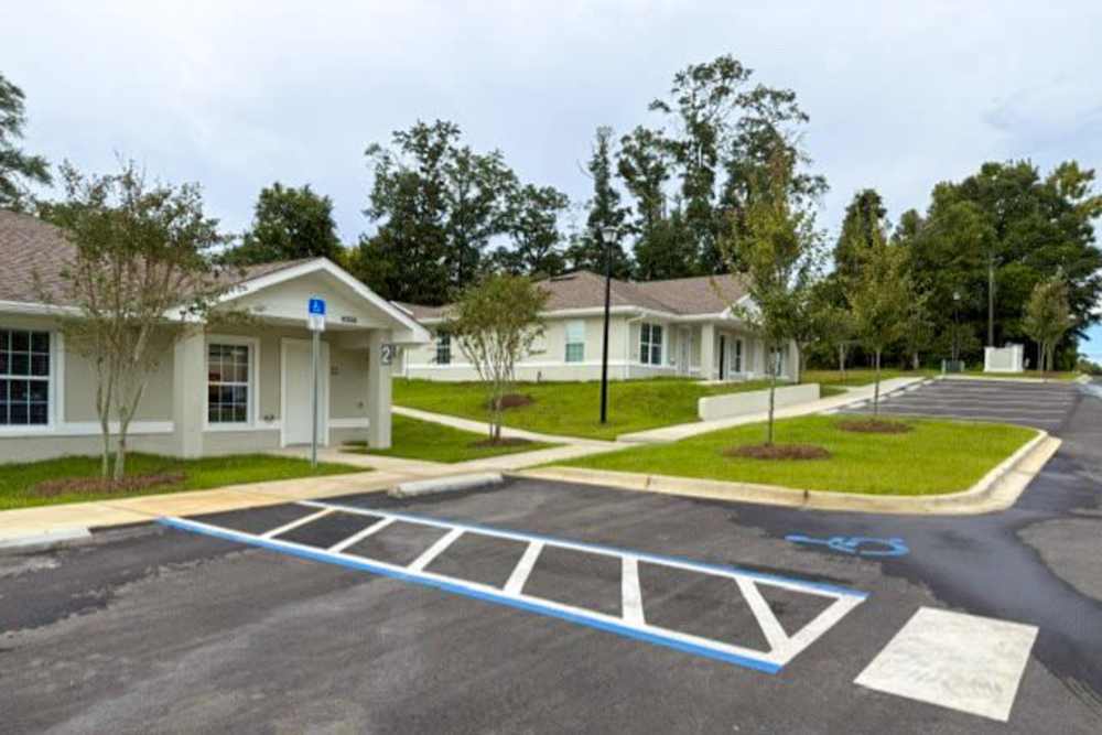 Gated apartment community with lush landscaping and accessible parking spaces at Village Springs Apartments in Defuniak Springs, Florida