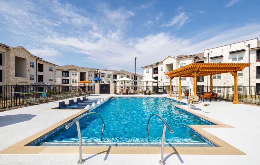 Sparkling resort-style pool with lounge chairs and shaded seating area under pergola at Preserve at Gresham Lake in Raleigh, North Carolina